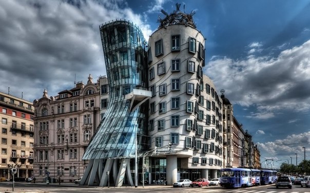 Танцующий дом, Прага, Чехия — офисное здание в Праге в стиле деконструктивизма, состоит из двух цилиндрических башен: нормальной и деструктивной. Танцующий дом является архитектурнойметафорой танцующей пары, в шутку называется «Джинджер и Фред» в честь пары Джинджер Роджерс и Фред Астер. Одна из двух цилиндрических частей, та, что расширяется кверху, символизирует мужскую фигуру (Фред) , а вторая часть здания визуально напоминает женскую фигуру с тонкой талией и развевающейся в танце юбкой (Джинджер). Как и многие деконструктивистские сооружения, резко контрастирует с соседствующим цельным архитектурным комплексом рубежа XIX—XX веков.