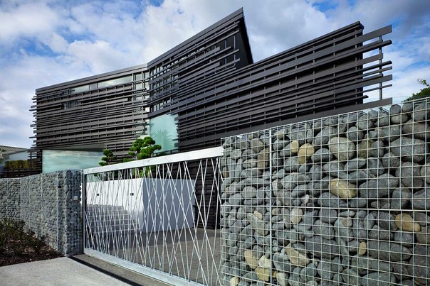 Архитектурная студия Bossley выполнила дизайн современного двухэтажного частного дома в Окленде, Новая Зеландия. Форма этого дома определена большими ограничениями участка со склоном и утёсом. Внешний фасад декорирован жалюзи из вертикальных металлических пластин, придающих проекту ультрасовременный вид.