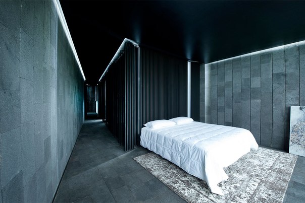 Архитектурная студия Joan Puigcorbé выполнила дизайн роскошного частного дома в Сьюдад- Колон, Коста-Рика. Дизайн проекта выполнен в серо-чёрной гамме. Темно серые поверхности каменного фасада продолжаются в интерьере. Потрясающий микс текстур — чёрные потолки, глянцевые поверхности, стекло, интегрированные линии света придают этому дому строгий ультрасовременный вид.